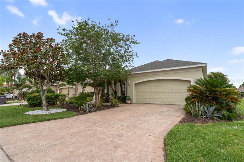 A single-story house with a beige exterior, a two-car garage, and a paved driveway — 11409 56TH STREET CIRCLE E, PARRISH, FL