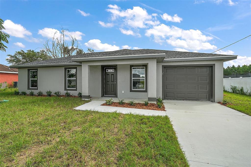 A single-story house with a gray exterior, a dark front door, and an attached garage — 23 OAK CIRCLE, OCALA, FL