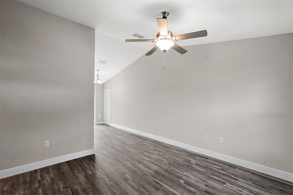 A room with light gray walls, dark wood-look flooring, and a ceiling fan — 23 OAK CIRCLE, OCALA, FL