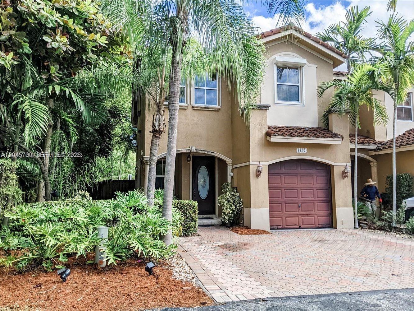 A two-story tan stucco house features a brown garage door and a brick paver driveway — 8853 SW 108th Pl, Miami FL 33176, MIAMI, FL