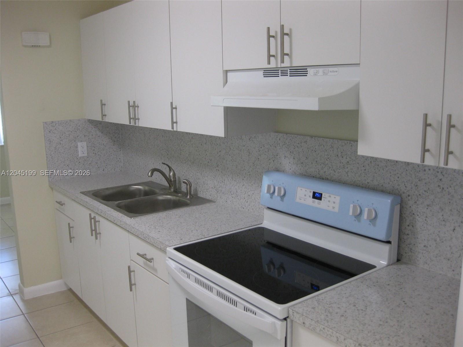 A kitchen features white cabinets, a speckled countertop, a double sink, and a light-blue stove — 1520 NE 14th St, Homestead FL 33033, HOMESTEAD, FL