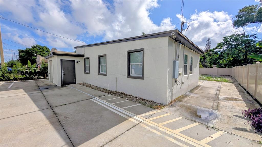 The exterior of a single-story commercial building with a concrete parking lot and white walls — 1245 N PINE HILLS ROAD, ORLANDO, FL