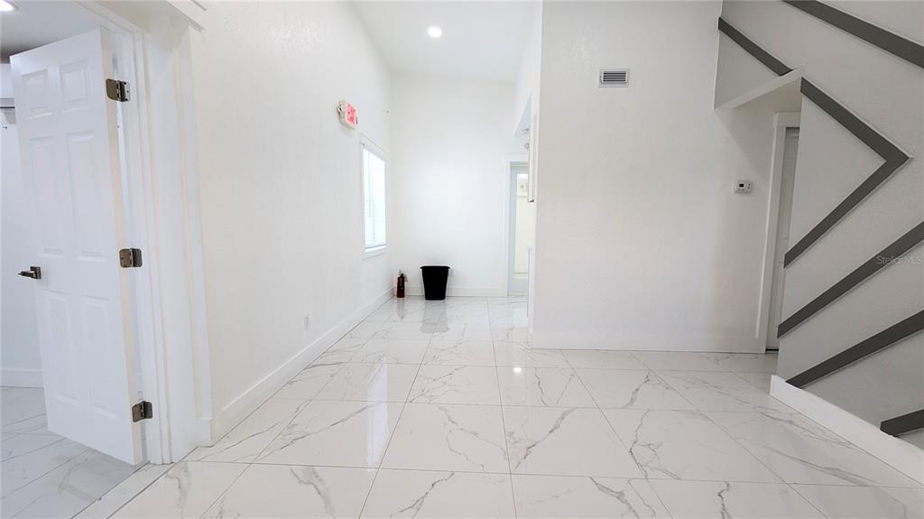 A bright room features white walls, large marble-patterned floor tiles, and a decorative wall accent — 1245 N PINE HILLS ROAD, ORLANDO, FL