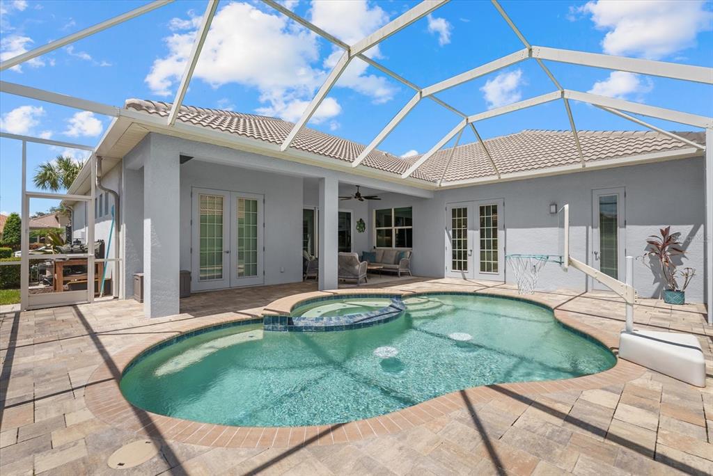 A screened-in patio features a swimming pool, a raised spa, and light-colored stone pavers — 489 ARBORVIEW LANE, VENICE, FL