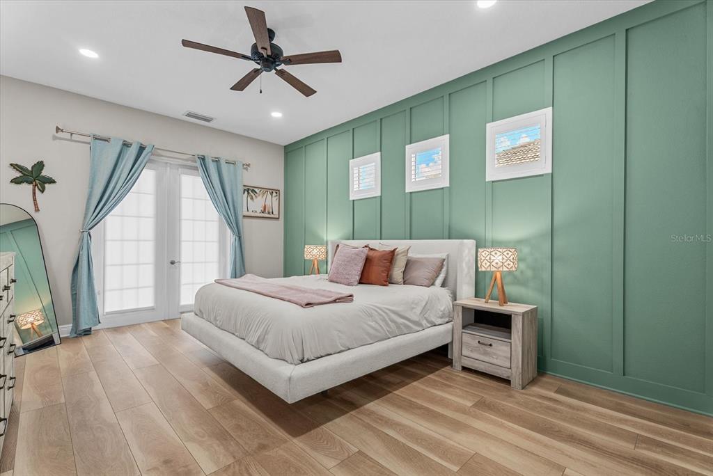 A bedroom features a green board-and-batten accent wall, a platform bed, and wood-look flooring — 489 ARBORVIEW LANE, VENICE, FL