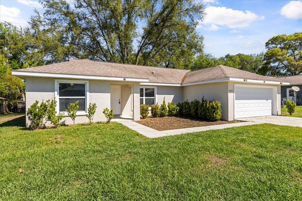 A single-story house with a beige stucco exterior, a shingled roof, and an attached garage — 5223 SE 135TH PLACE, SUMMERFIELD, FL