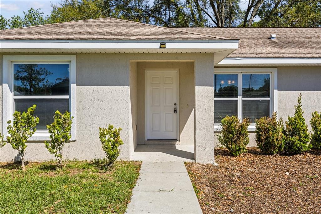 The exterior of a single-story house features a white front door and two windows — 5223 SE 135TH PLACE, SUMMERFIELD, FL