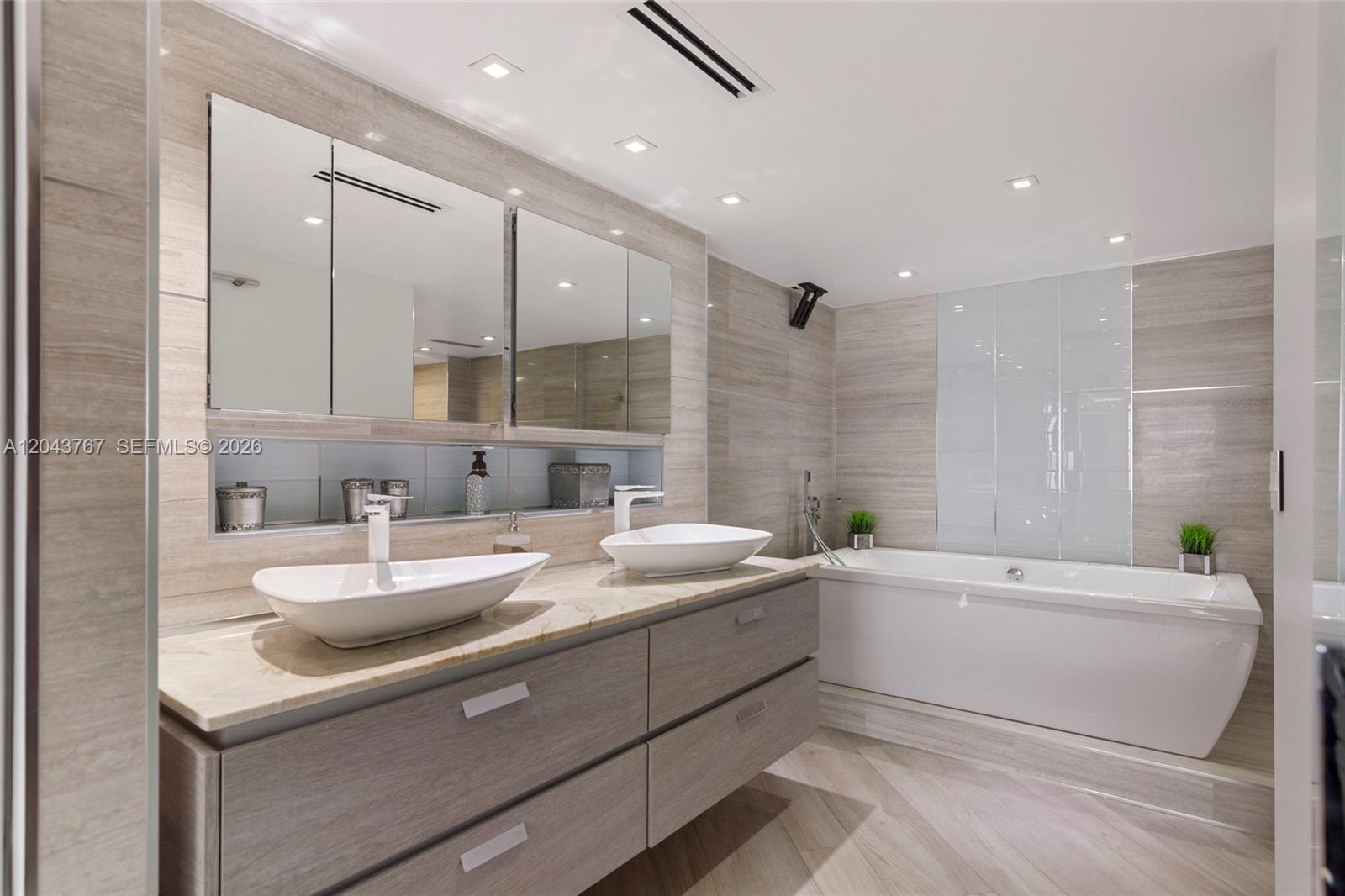 A modern bathroom features a double vanity with vessel sinks, a soaking tub, and tile — 6061 Collins Ave # 8F, Miami Beach FL 33140, MIAMI BEACH, FL