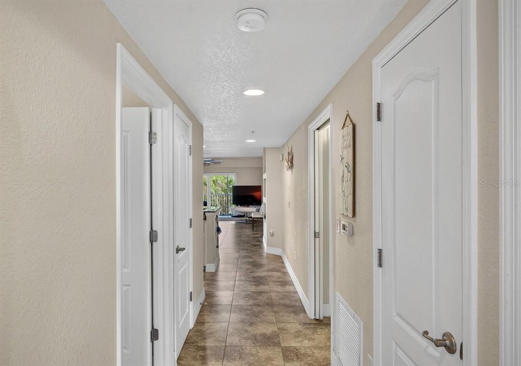 A hallway with tile flooring leads toward a living area with a television and balcony — 5300 S ATLANTIC AVENUE UNIT 19-203, NEW SMYRNA BEACH, FL