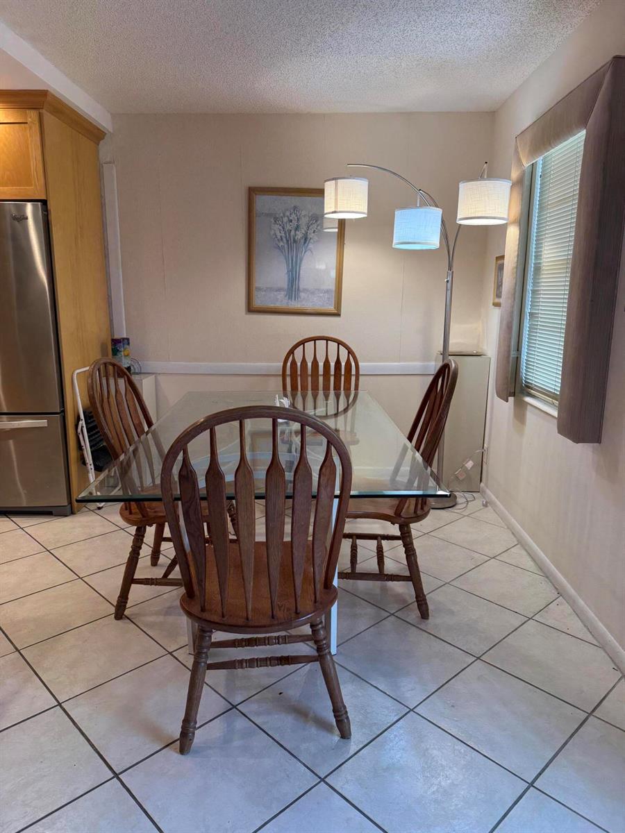 A dining area features a glass-topped table, four wooden chairs, and a three-light floor lamp — 1046 Wolverton C, Boca Raton FL 33434, BOCA RATON, FL