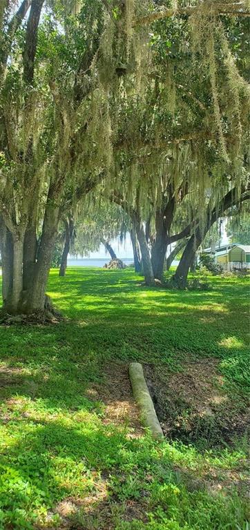A grassy yard with large, moss-draped trees leads toward a distant view of the water — BEACH PARKWAY, LAKE WALES, FL