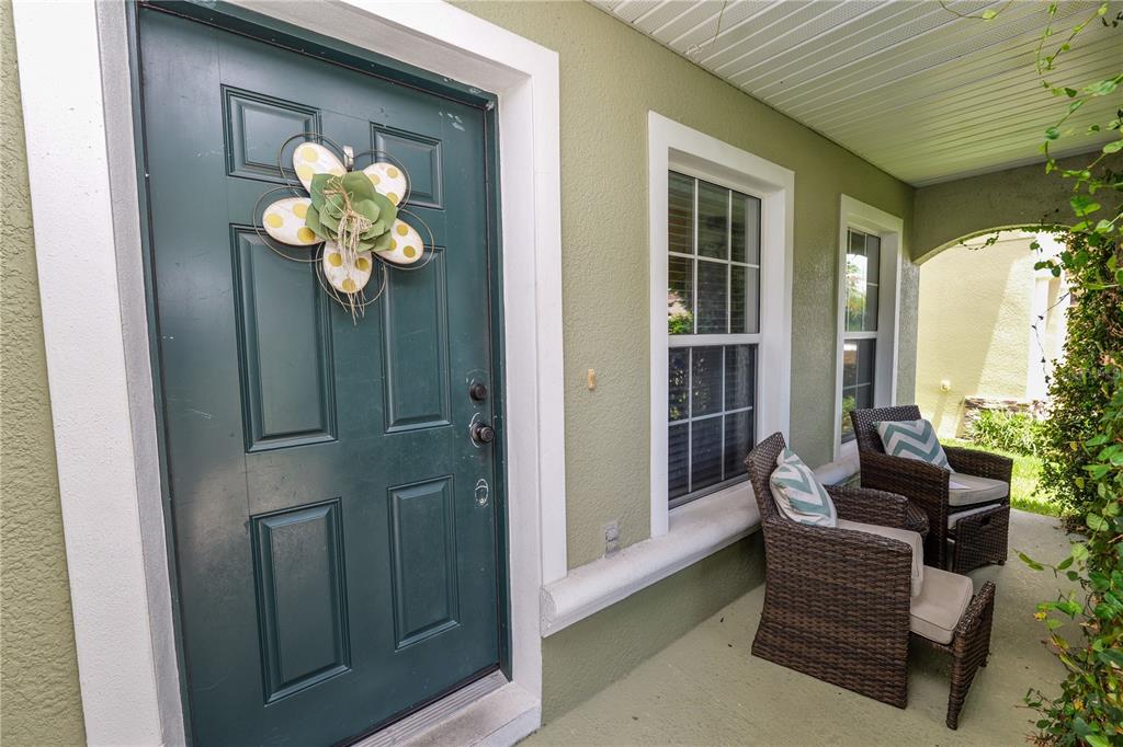 A green front door with a floral wreath sits on a porch with two chairs — 2316 GENEVA DRIVE, LAKELAND, FL