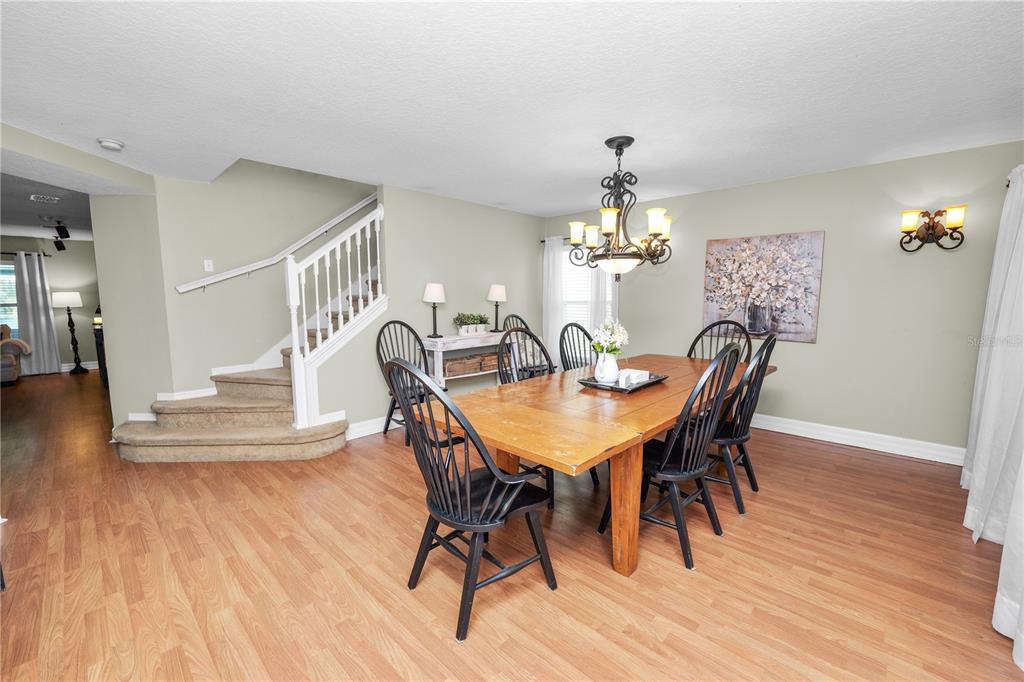 A dining room features a wooden table, black chairs, a chandelier, and a carpeted staircase — 2316 GENEVA DRIVE, LAKELAND, FL