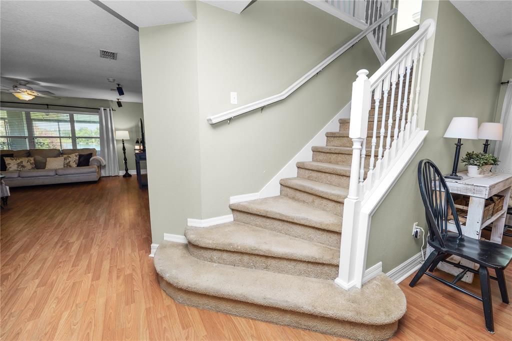 A carpeted staircase with a white railing stands in a room with light-colored walls — 2316 GENEVA DRIVE, LAKELAND, FL
