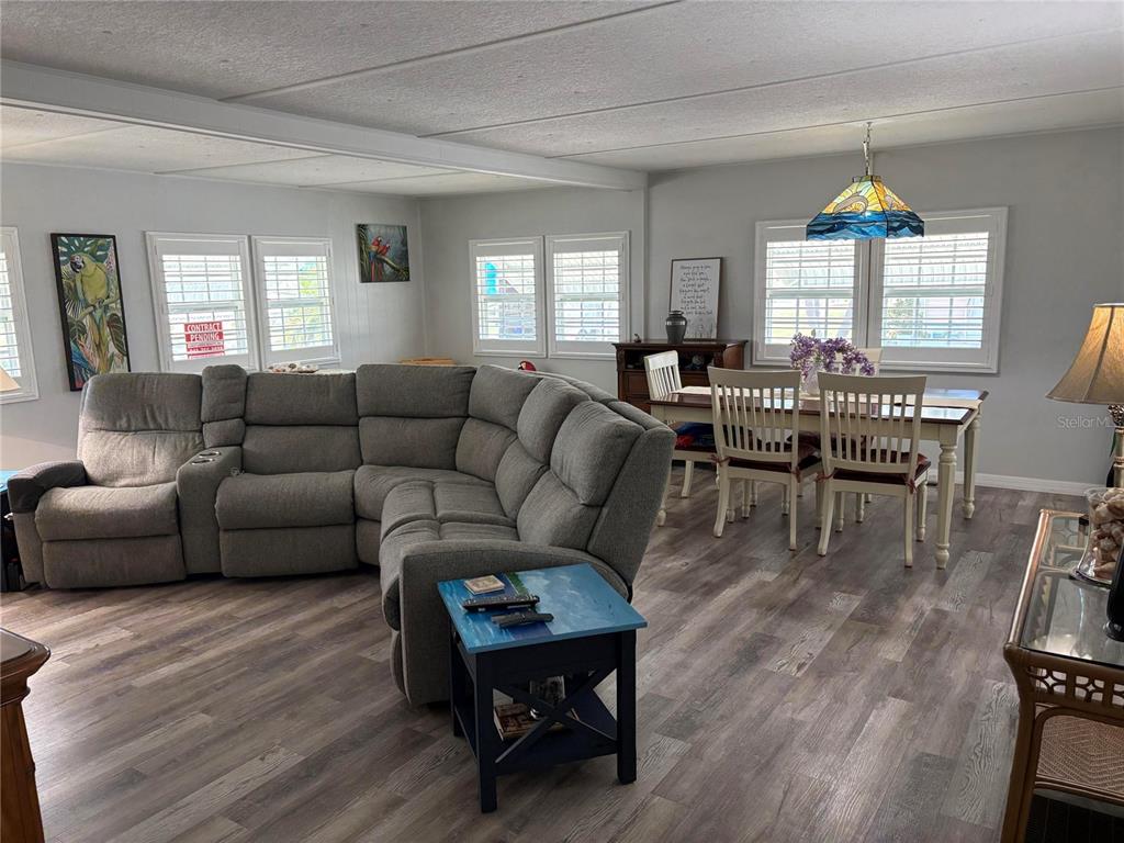 A living and dining area features a large gray sectional, wood-look flooring, and a pendant light — 408 49TH A AVENUE E, BRADENTON, FL