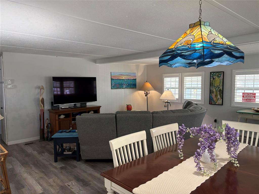 A dining area with a wooden table leads into a living room with a gray sectional — 408 49TH A AVENUE E, BRADENTON, FL