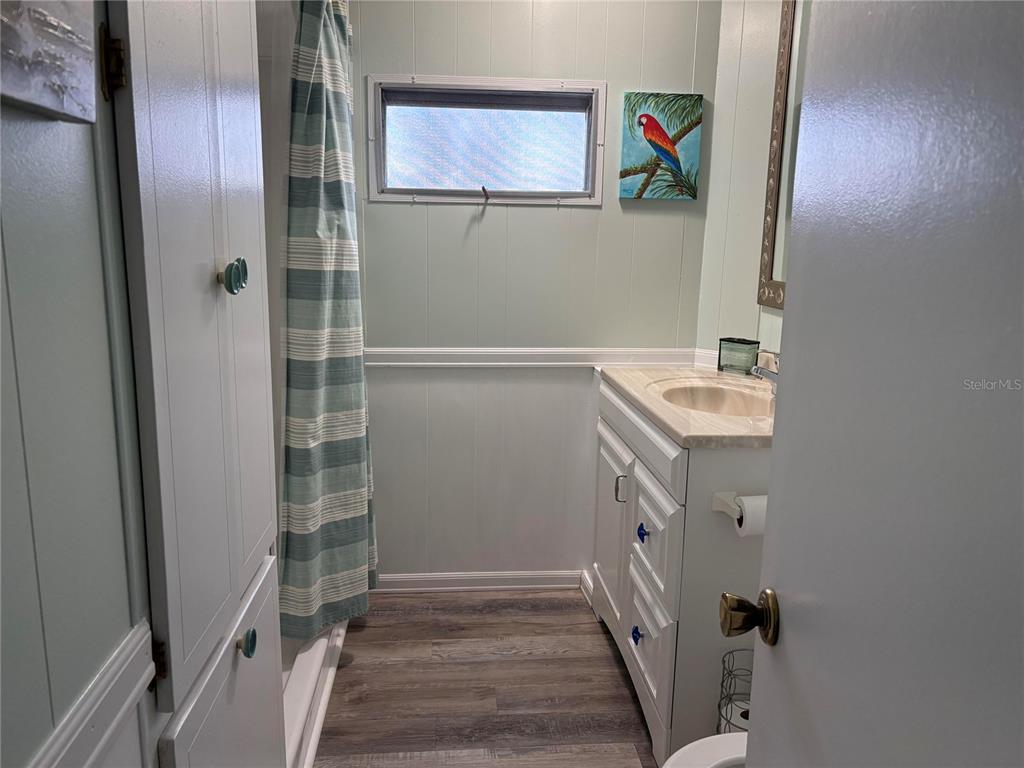 A bathroom features a vanity, a shower with a striped curtain, and light green walls — 408 49TH A AVENUE E, BRADENTON, FL