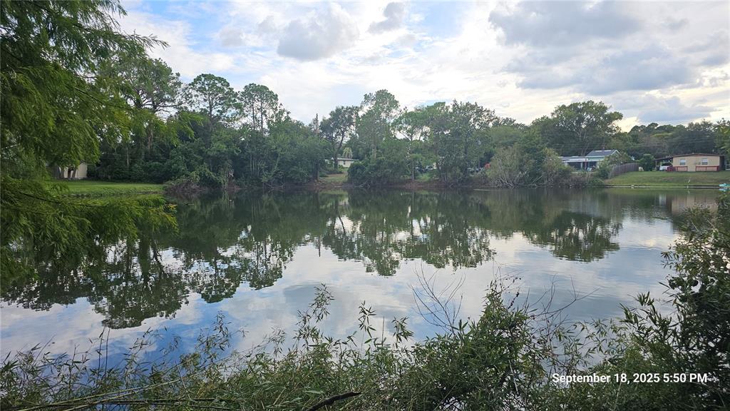 A view of a calm pond surrounded by trees and residential homes in the distance — 691 PIEDMONT DRIVE, DELTONA, FL