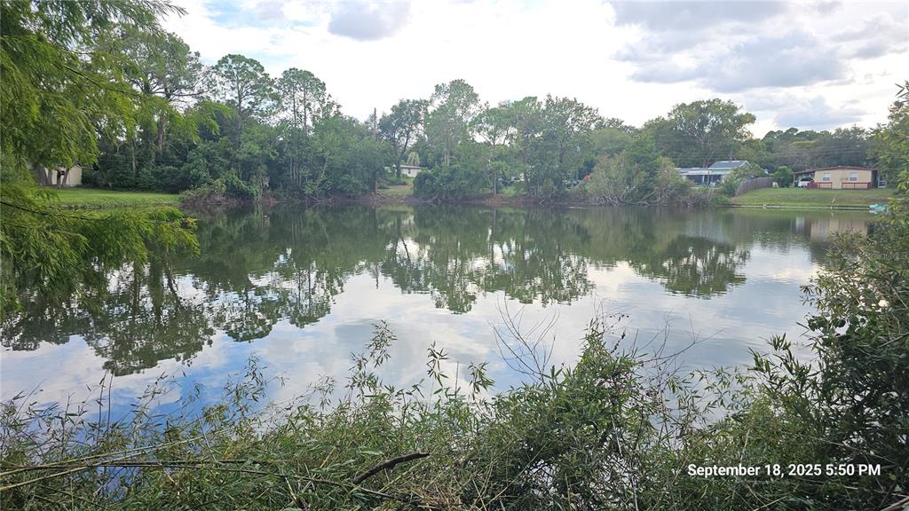 A view of a calm pond surrounded by trees and residential homes in the distance — 691 PIEDMONT DRIVE, DELTONA, FL