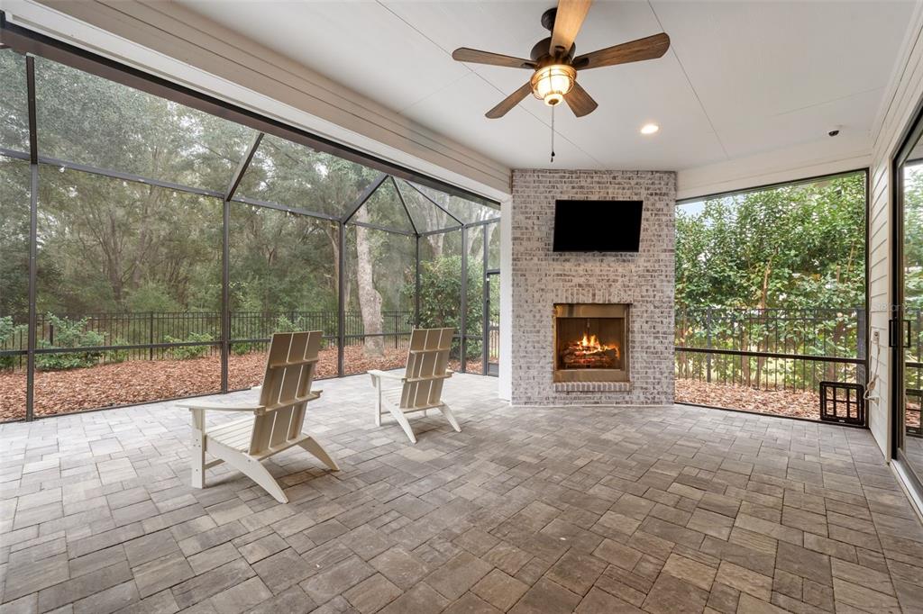 A screened-in patio features a brick fireplace, a ceiling fan, and two white chairs — 11081 SW 38TH BOULEVARD, GAINESVILLE, FL