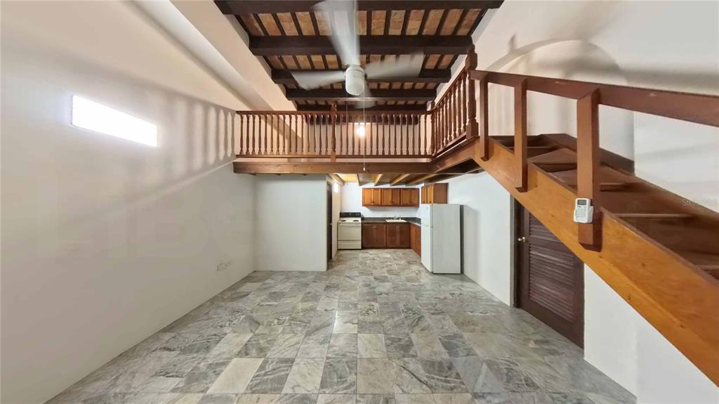 An open-plan living area features a kitchen, tiled floors, and a wooden staircase to a loft — 152 SAN JUSTO STREET, SAN JUAN, PR