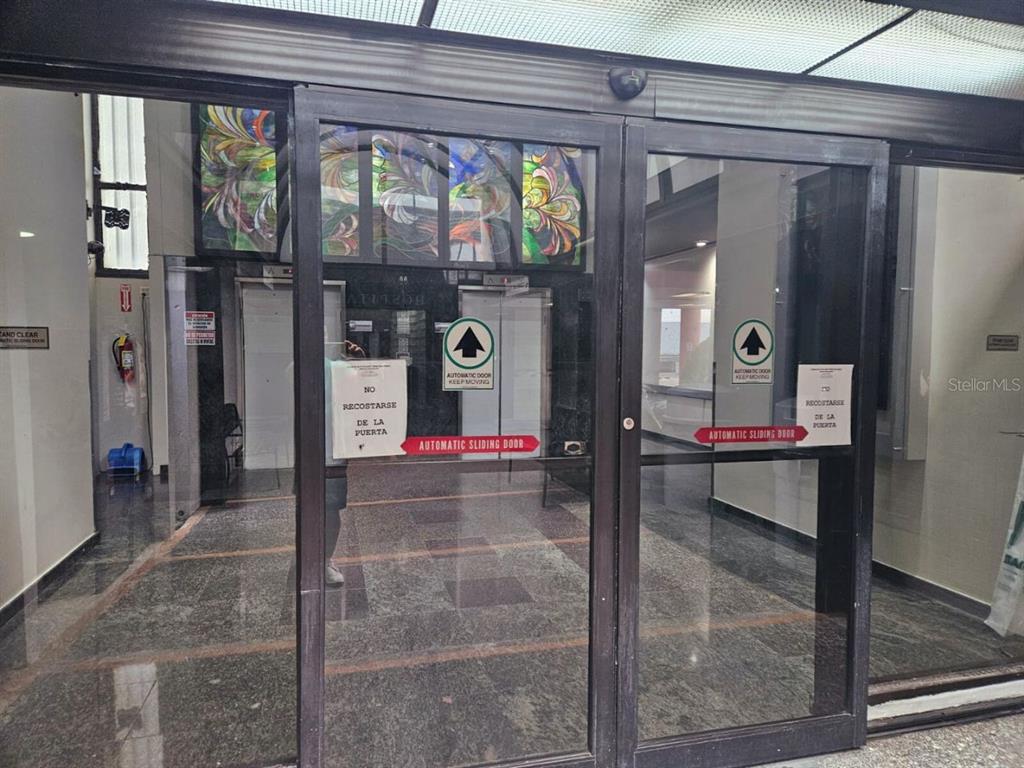A set of automatic sliding glass doors leads into a lobby with marble flooring — 57 SANTA CRUZ UNIT 1, BAYAMON, PR