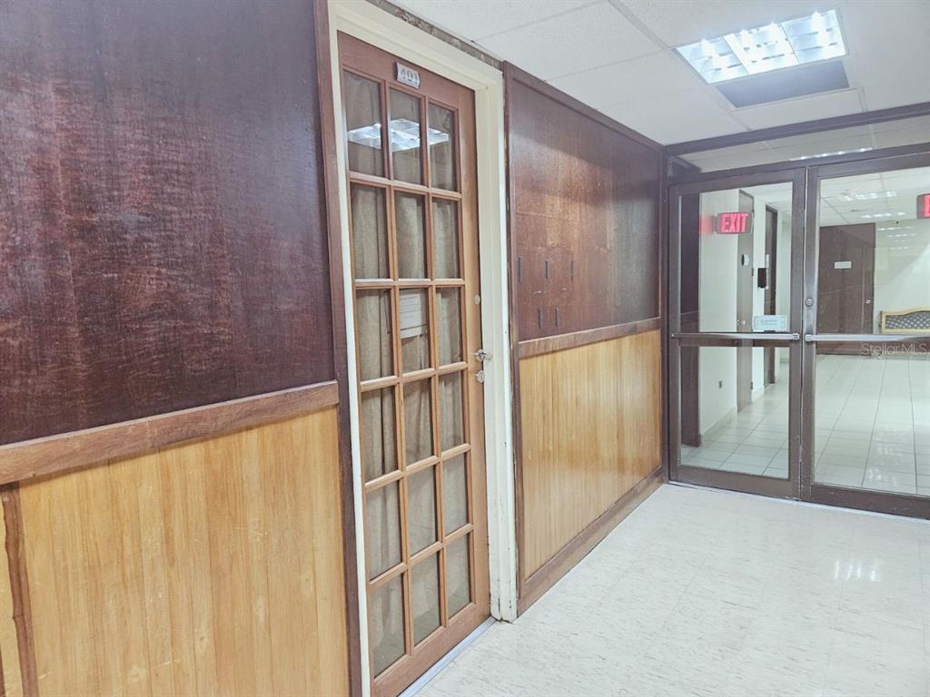 A hallway features wood-paneled walls, a glass-paned door labeled 401, and a glass exit door — 57 SANTA CRUZ UNIT 1, BAYAMON, PR