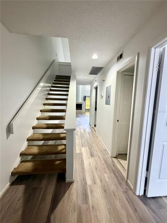 An interior hallway features wood-look flooring, a carpeted staircase, and white walls — 498 CLUB DRIVE, WINTER SPRINGS, FL