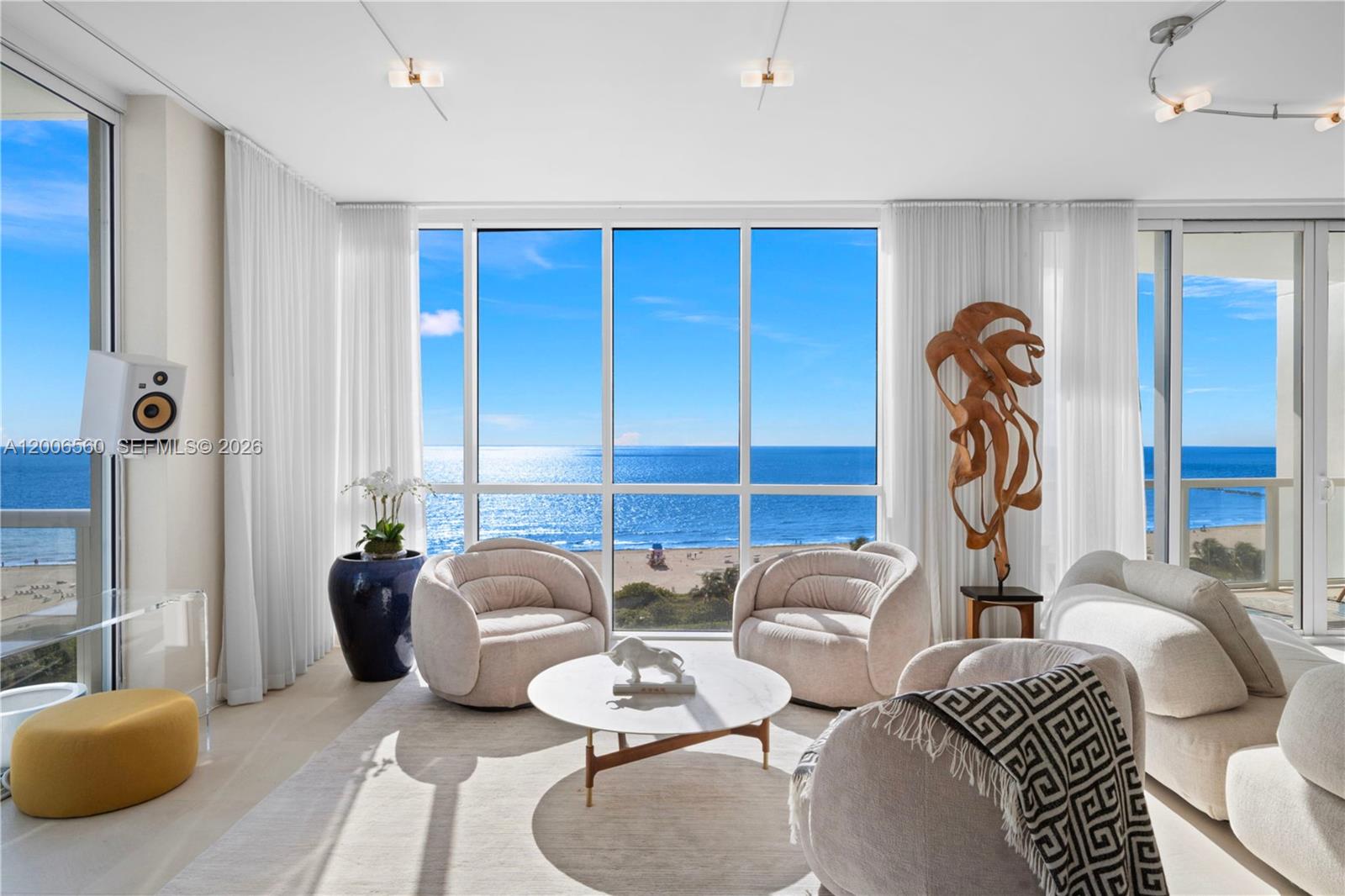 A bright living room features plush seating, a marble coffee table, and floor-to-ceiling ocean views — 50 S Pointe Dr, Miami Beach FL 33139, MIAMI BEACH, FL