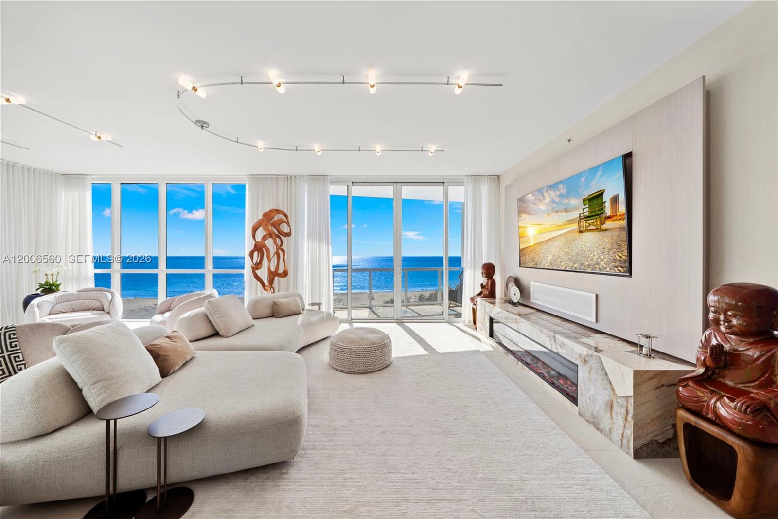 A modern living room features a large sectional sofa, fireplace, and floor-to-ceiling ocean views — 50 S Pointe Dr, Miami Beach FL 33139, MIAMI BEACH, FL