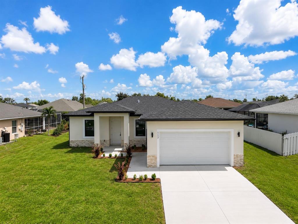 A single-story house with a white garage, stone accents, and a dark shingled roof — 117 NW 13TH STREET, CAPE CORAL, FL