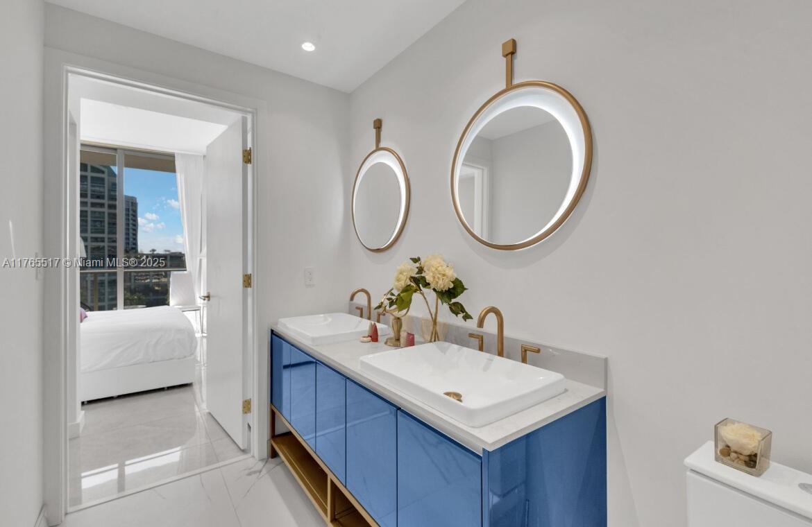 A bathroom features a blue double vanity, vessel sinks, and two round backlit mirrors — 2678 Tigertail # 1009, Miami FL 33133, MIAMI, FL