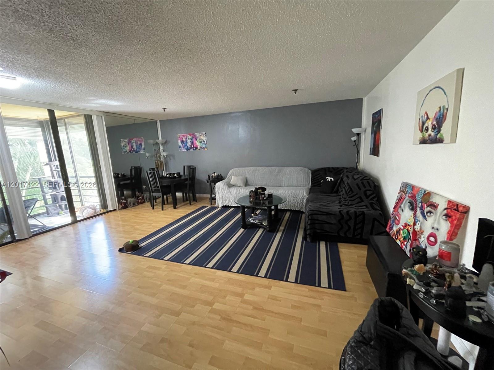 A living room features light wood flooring, a striped rug, and a gray accent wall — 671 NE 195th St, Miami FL 33179, MIAMI, FL