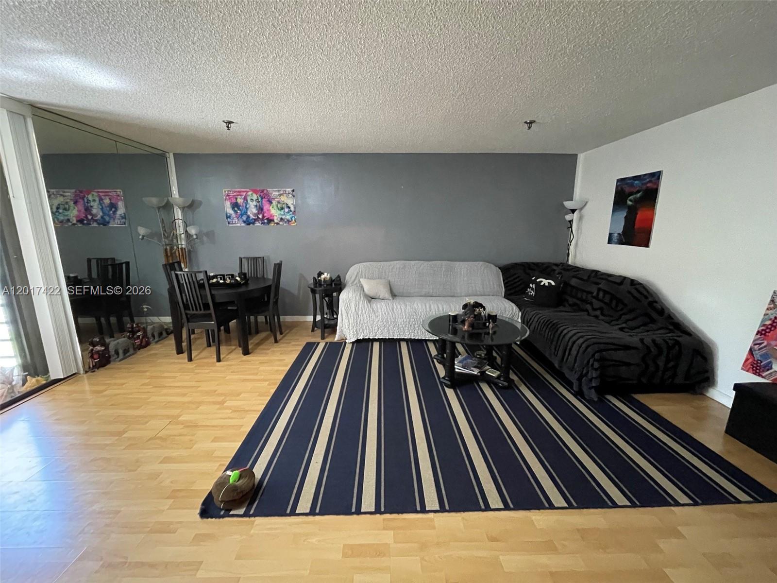 A living room features a striped rug, gray accent wall, and a sectional sofa — 671 NE 195th St, Miami FL 33179, MIAMI, FL
