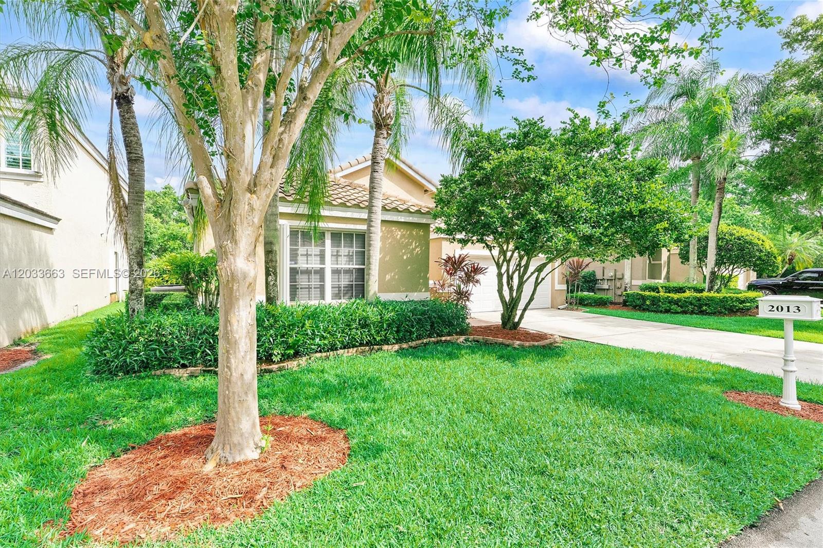 A one-story suburban house with a tan exterior, tile roof, and a landscaped front yard — 2013 Island Cir, Weston FL 33326, WESTON, FL