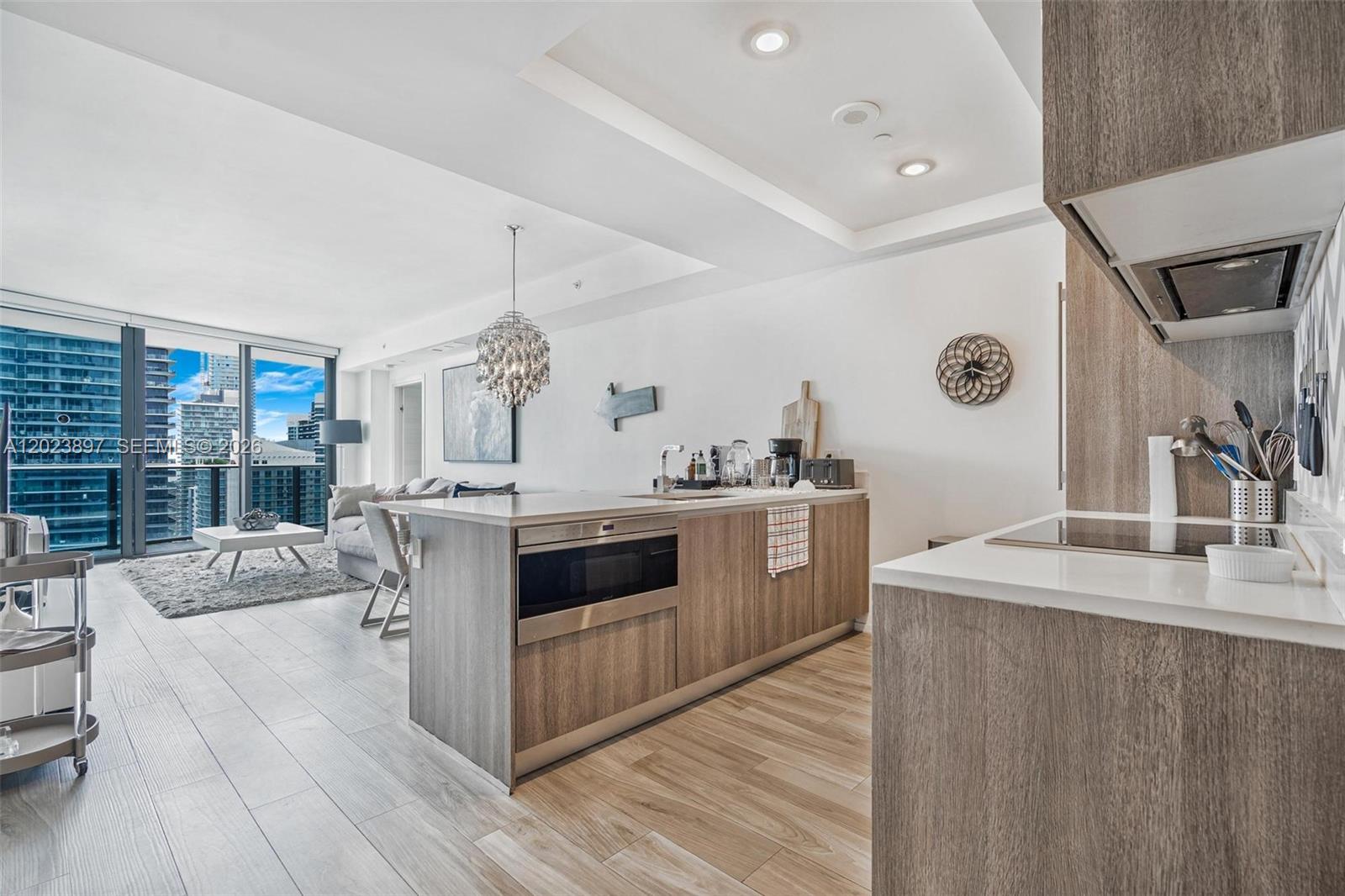 A modern kitchen island with a built-in microwave faces a living area with floor-to-ceiling windows — 801 S Miami Ave # 4302, Miami FL 33130, MIAMI, FL