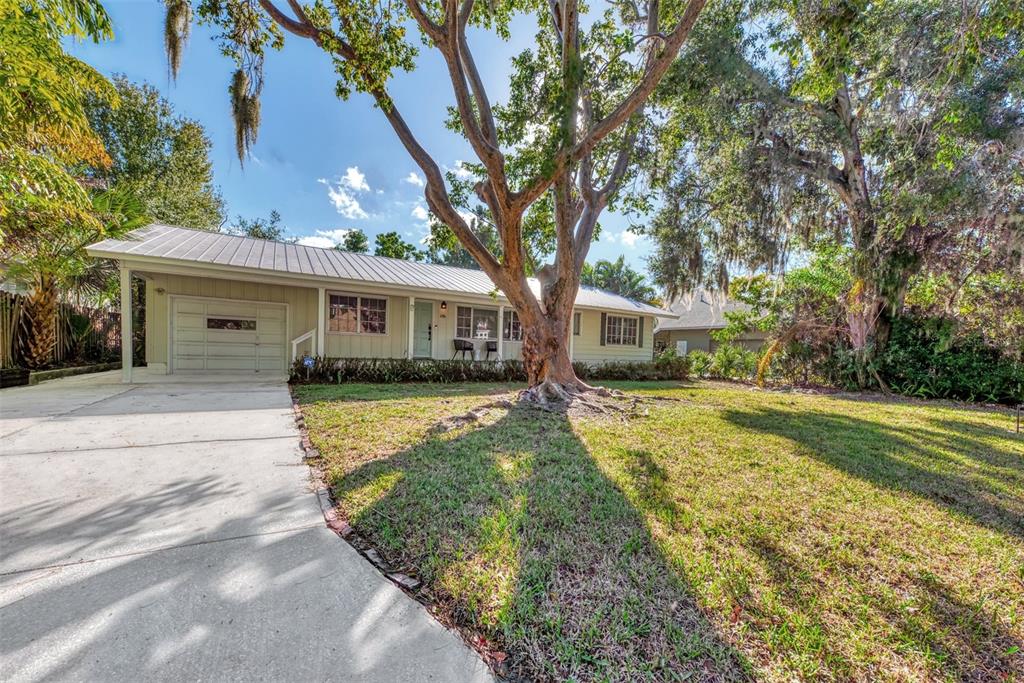 A single-story house with a metal roof, attached garage, and a large tree in front — 1726 FLOYD STREET, SARASOTA, FL