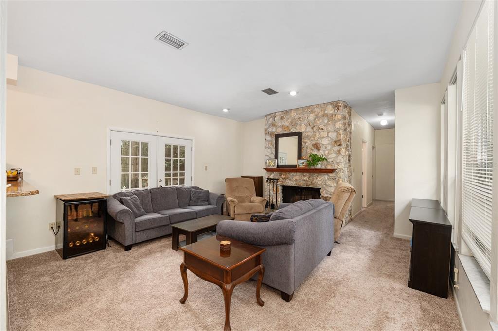 A living room features a stone fireplace, two gray sofas, and beige carpeting — 315 NW 28TH STREET, GAINESVILLE, FL