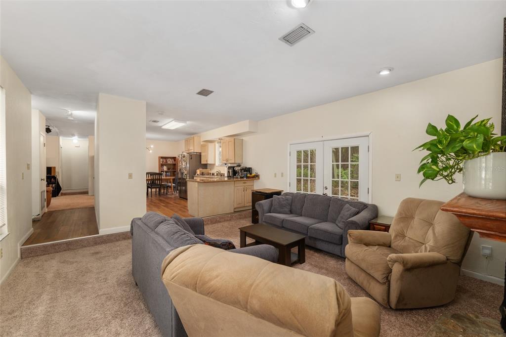 A living room with gray sofas and carpeted floors opens to a kitchen with wood cabinets — 315 NW 28TH STREET, GAINESVILLE, FL
