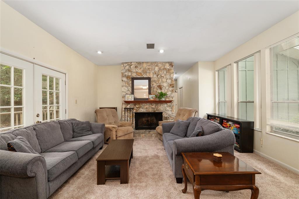 A living room features two gray sofas, a stone fireplace, and a coffee table — 315 NW 28TH STREET, GAINESVILLE, FL