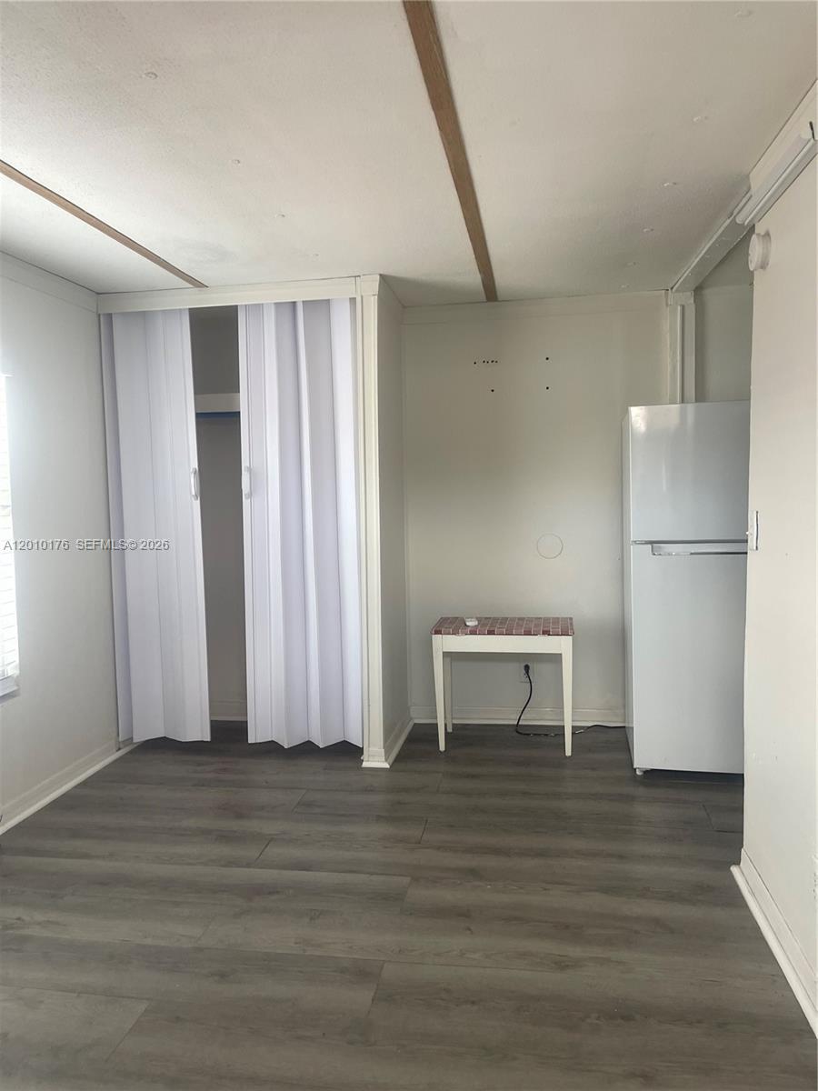 A room features gray wood-look flooring, a white refrigerator, a small table, and a closet — 12401 W Okeechobee Rd, Hialeah FL 33018, HIALEAH, FL