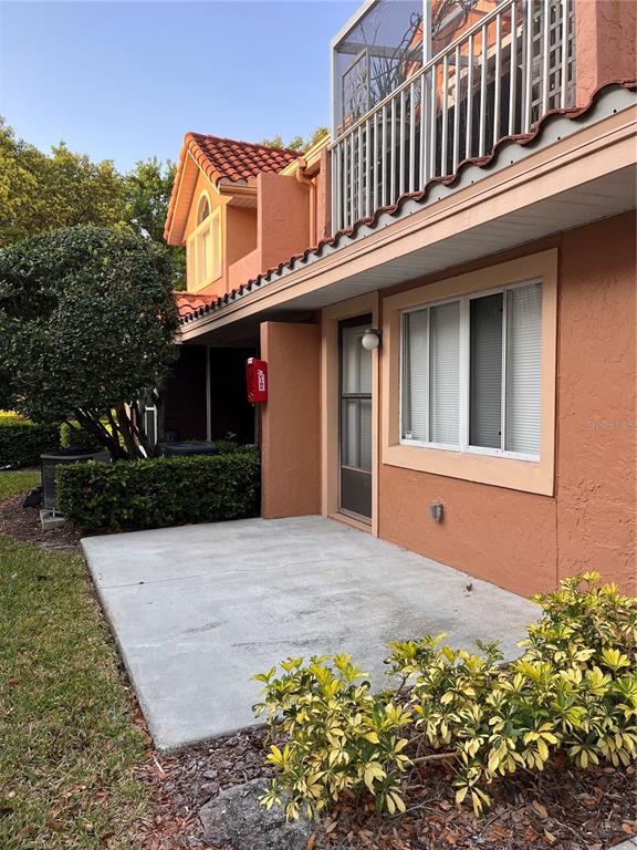 A concrete patio sits in front of a tan building with a screened-in balcony above — 8304 WATERVIEW WAY UNIT 8304, WINTER HAVEN, FL