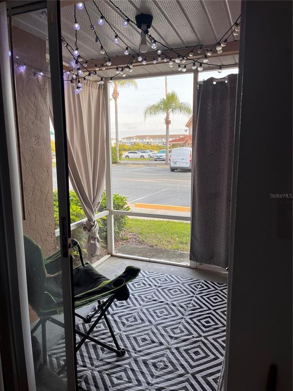 A screened-in porch features a geometric rug, a folding chair, string lights, and outdoor curtains — 8304 WATERVIEW WAY UNIT 8304, WINTER HAVEN, FL
