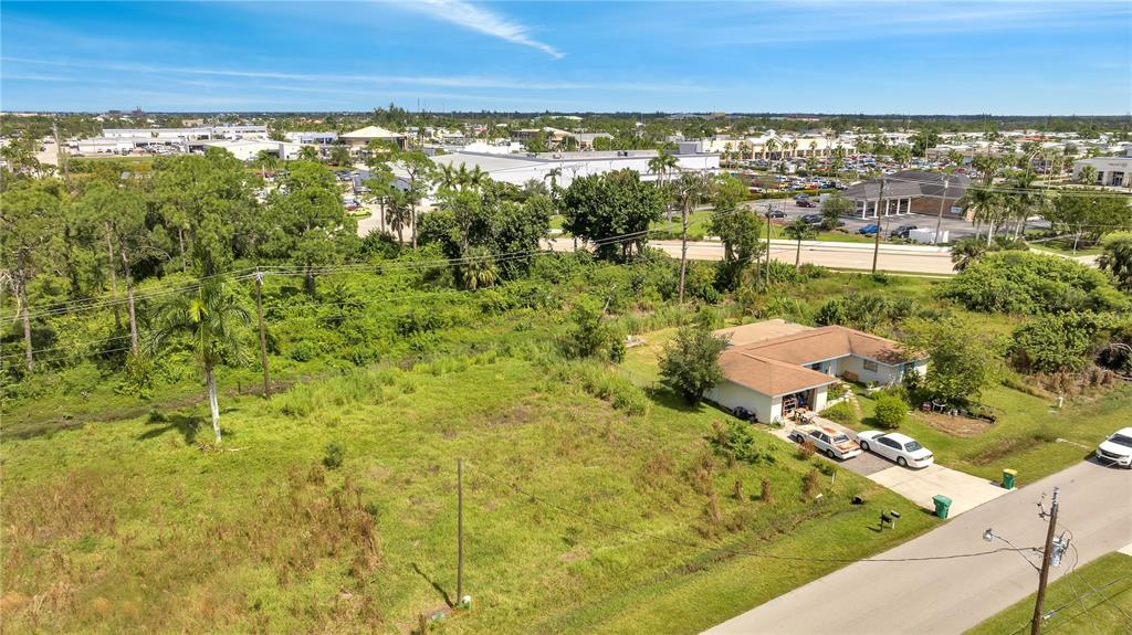 An aerial view shows a single-story house with a large, grassy lot and surrounding vegetation — 230 POMPANO TERRACE, PUNTA GORDA, FL