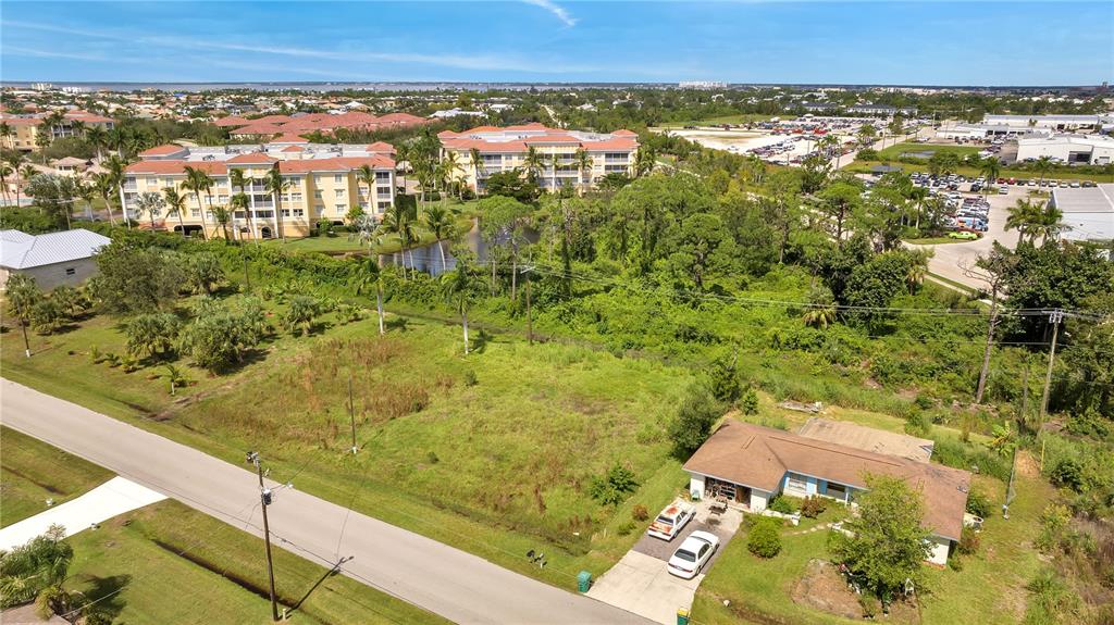 An aerial view shows a single-story house, a vacant lot, and nearby apartment buildings — 230 POMPANO TERRACE, PUNTA GORDA, FL
