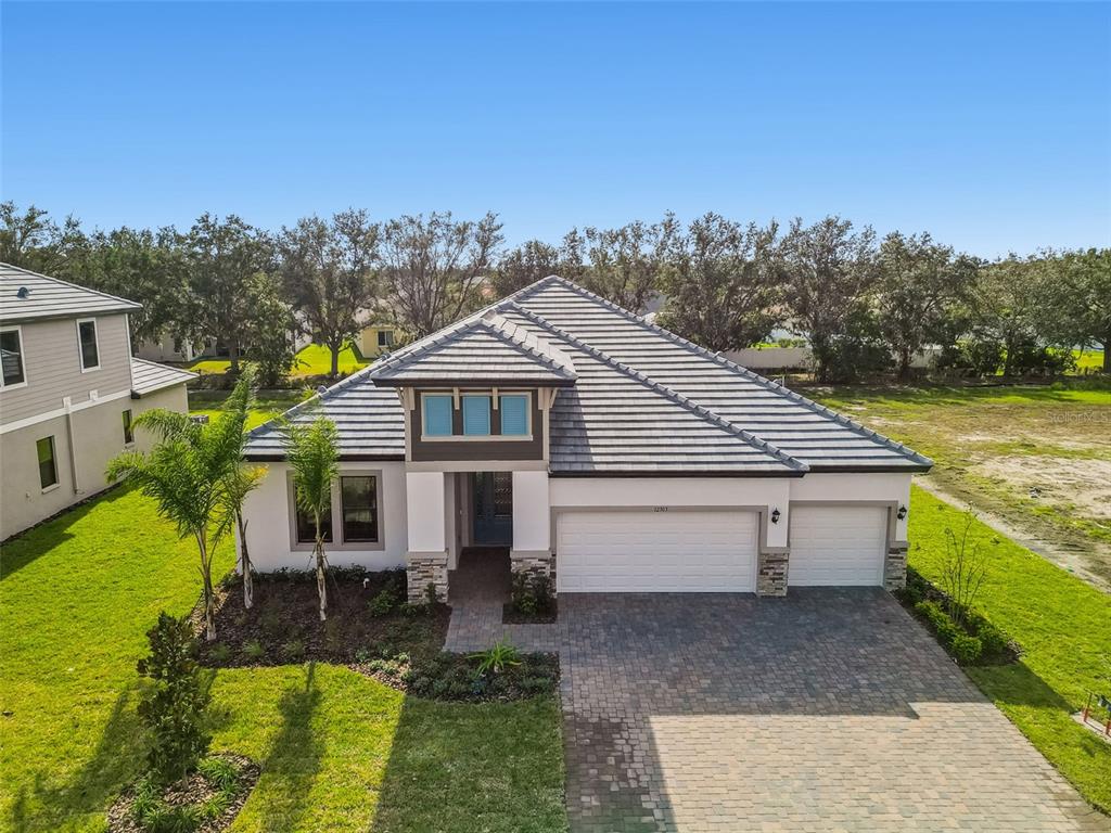 A single-story house with a gray tile roof, white stucco exterior, and a paved driveway — 12305 WHITE BLOSSOM COURT, PARRISH, FL