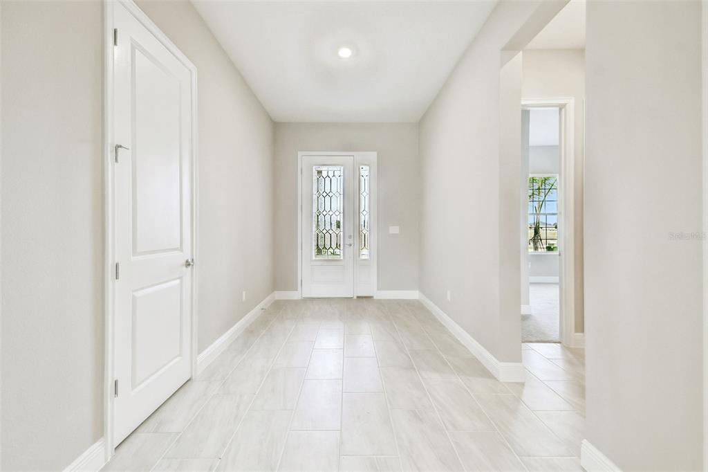 A bright entryway features light-colored tile flooring, white trim, and a decorative glass front door — 12305 WHITE BLOSSOM COURT, PARRISH, FL