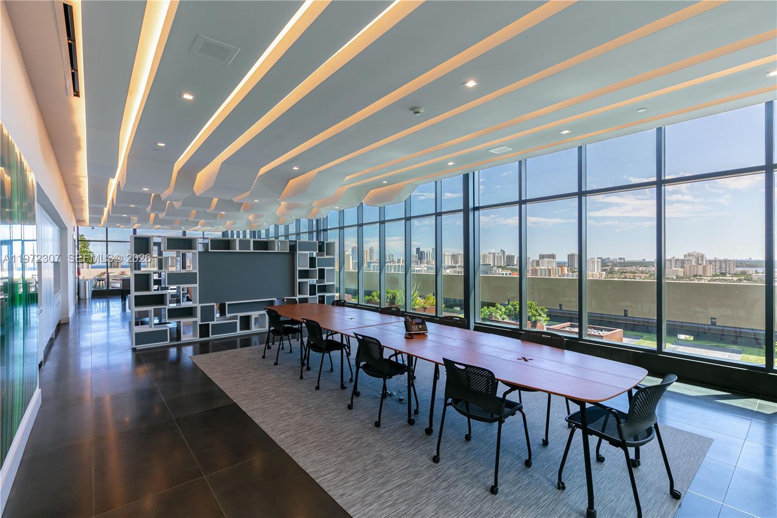 A modern conference room features a long wooden table, black chairs, and floor-to-ceiling windows — 19790 W Dixie Hwy 1004 Hwy, FL 33180, FL