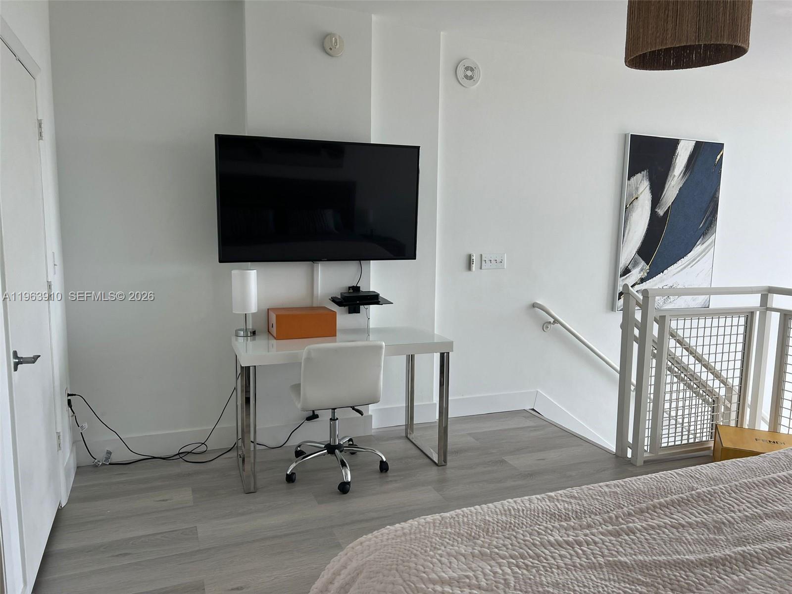 A loft bedroom features a gray bed, a white desk, a ceiling fan, and large windows — 253 NE 2nd St # 433, Miami FL 33132, MIAMI, FL