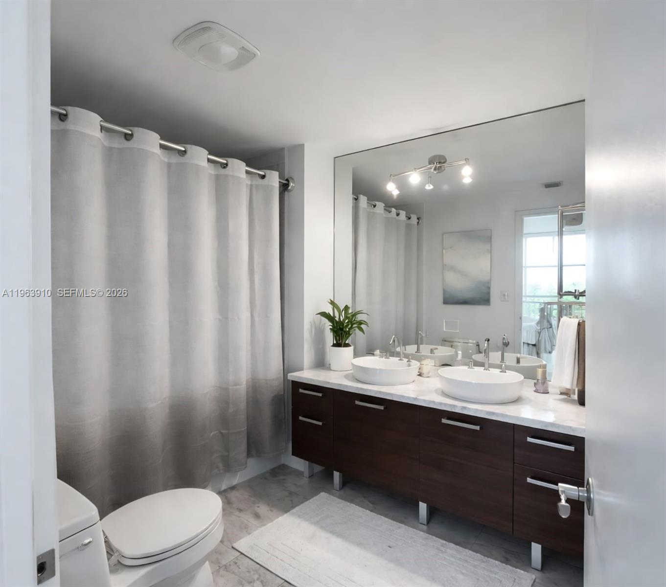 A bedroom loft features a gray bed, wood-look flooring, and a metal railing overlooking windows — 253 NE 2nd St # 433, Miami FL 33132, MIAMI, FL